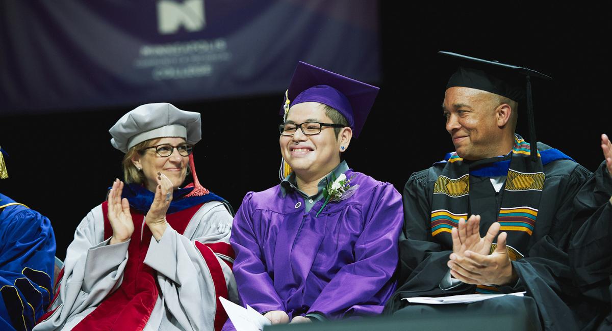Minneapolis College two vice presidents applauding recent graduate of Minneapolis College at the Graduation Ceremony.