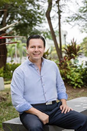 Dr Pacheco sitting on a bench, trees in background