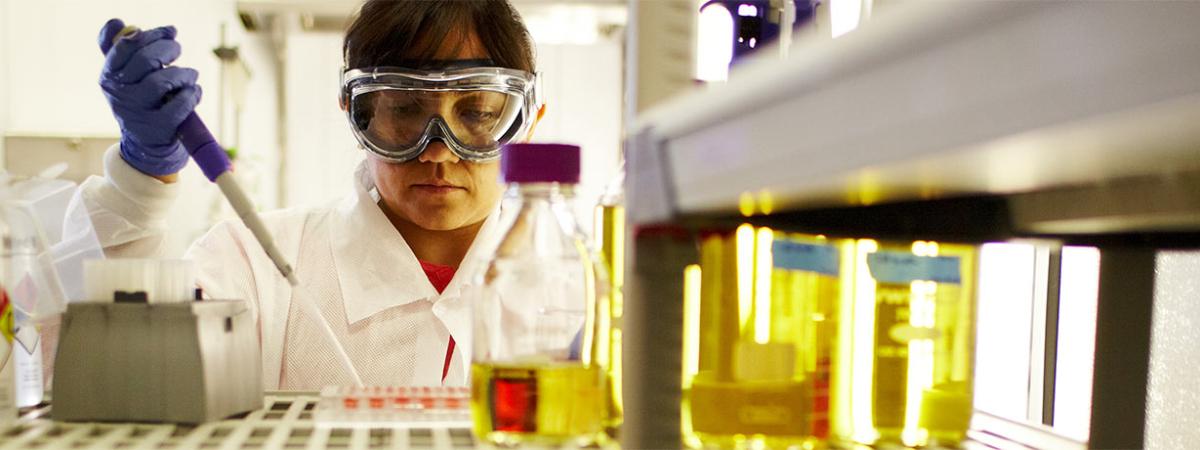 Student performing a biology procedure with flasks in class at Minneapolis College