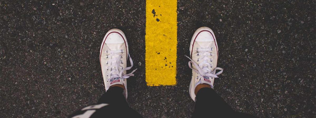 Let Us Help You Choose Your Best Path Jogger shoes between a lane stripe on a road