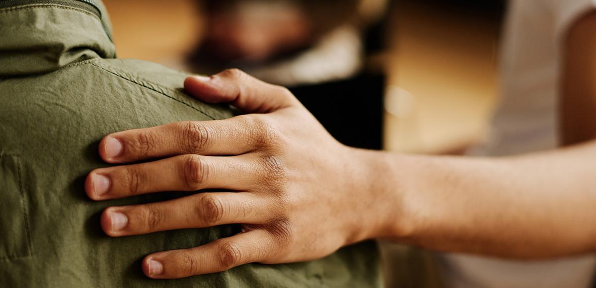 A supportive hand placed on a person's shoulder. 