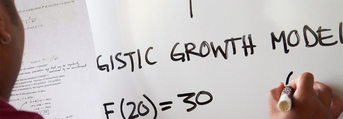 Economics Program at Minneapolis College student writing assignment on a white board