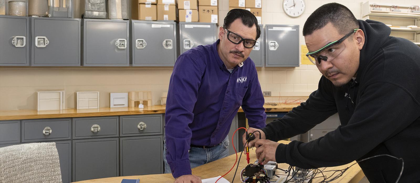 A student and HVACR instructor work with equipment in the lab. 