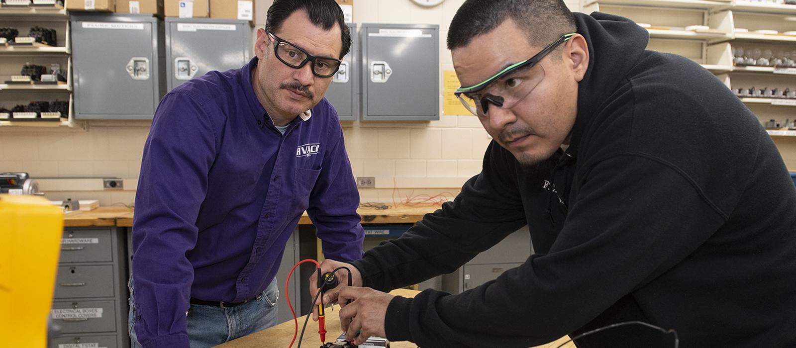 An HVACR instructor works with a student who is using components.  