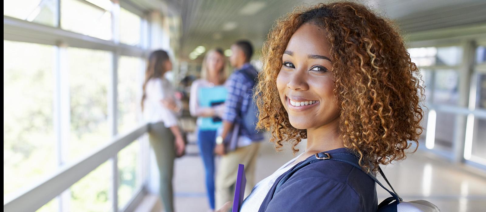 A student looking over her shoulder, a group of students can be seen in the distance in the background. 