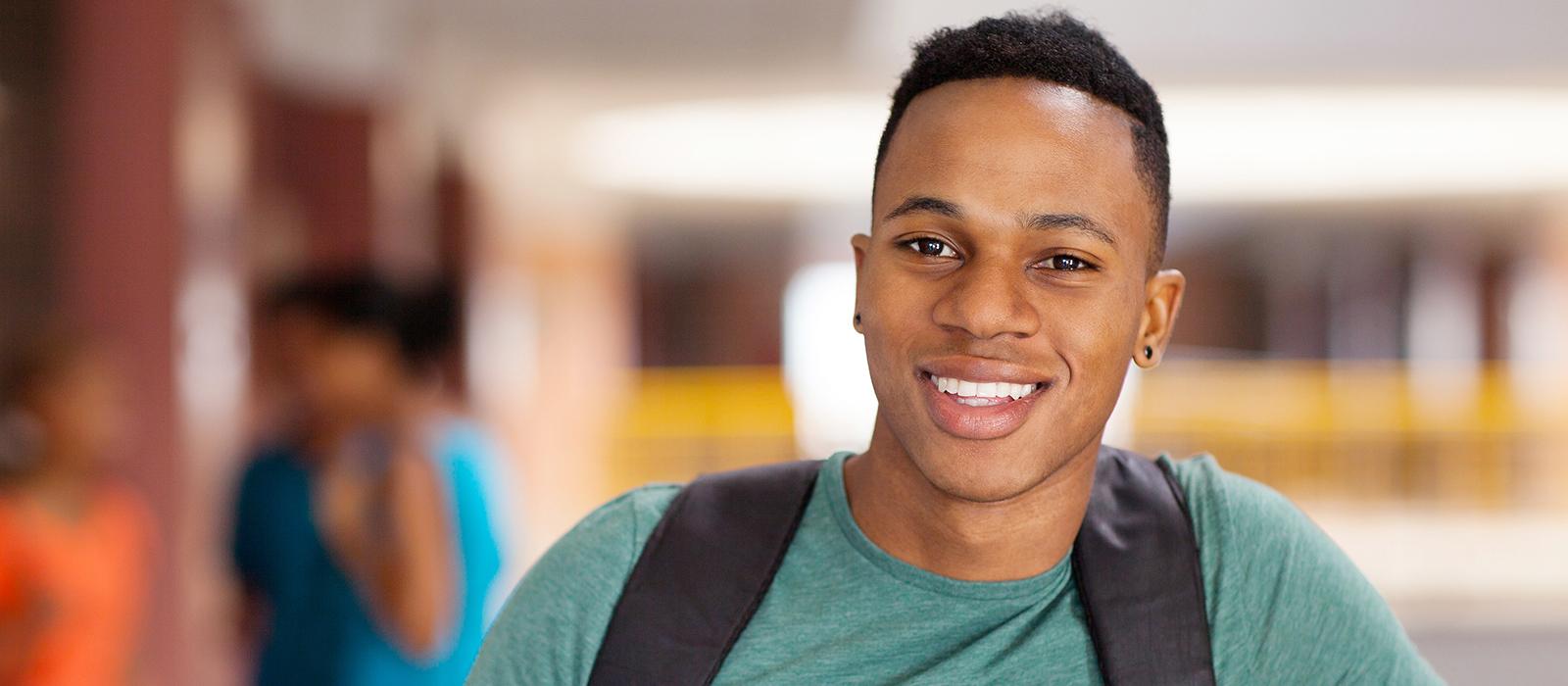 A male student wearing a back pack, smiling. 
