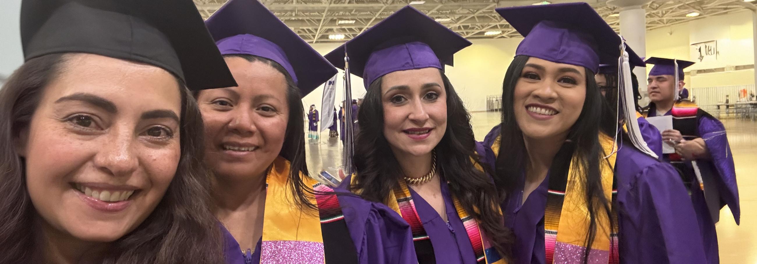 Four women in caps and gowns standing next to each other at Commencement ceremony 