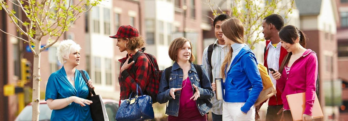 A group of students socializing while waiting for a city bus