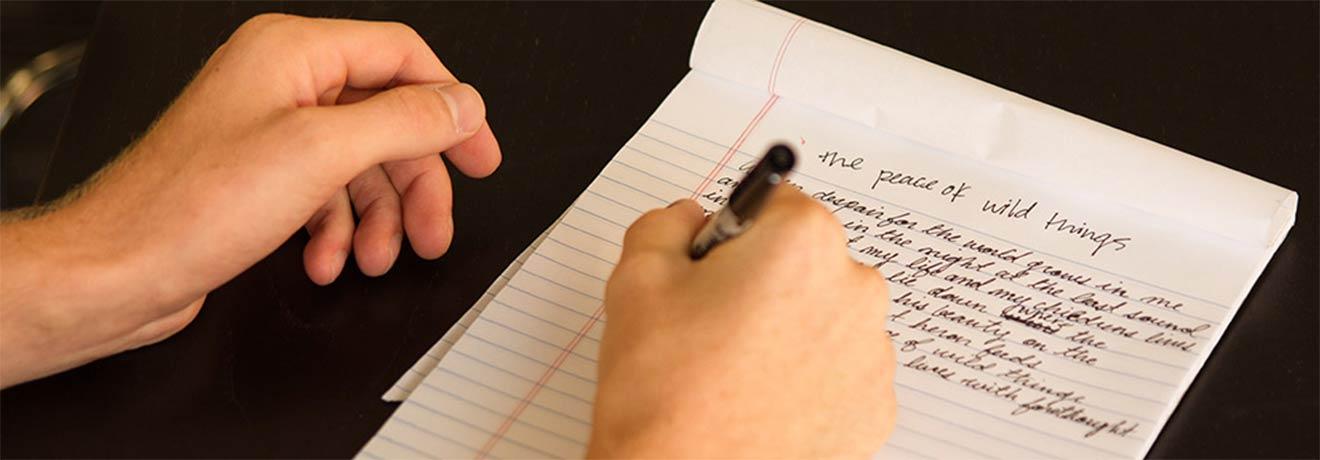 a right-handed person writing a short story on a tablet of paper