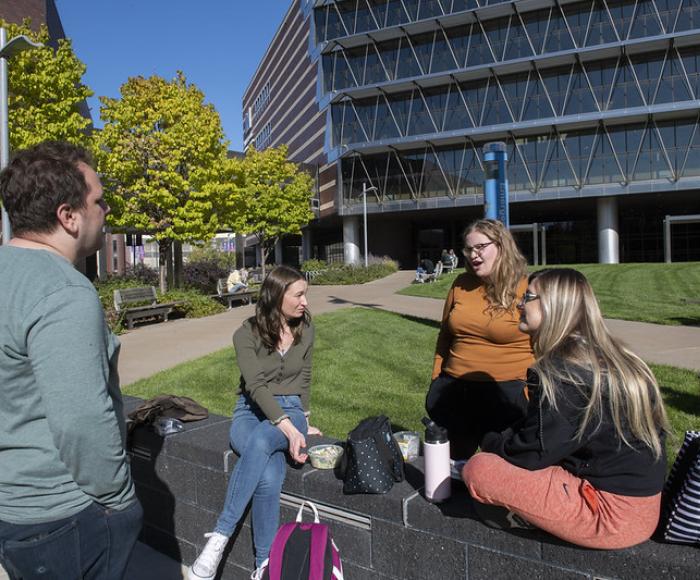 Four students outside in the courtyard talking