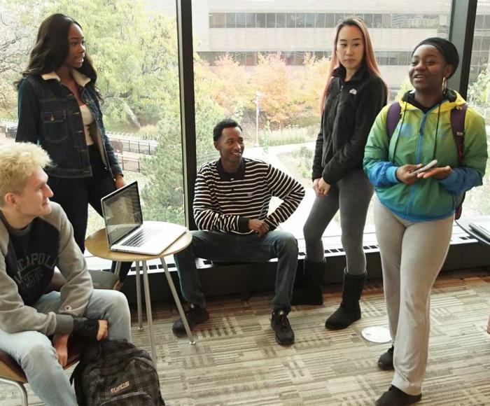 Admissions at Minneapolis College Students gathering and talking in an open area of a campus building