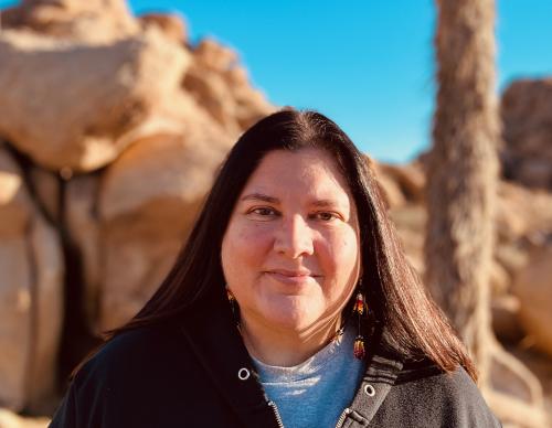 Headshot of smiling Native American woman with desert in background