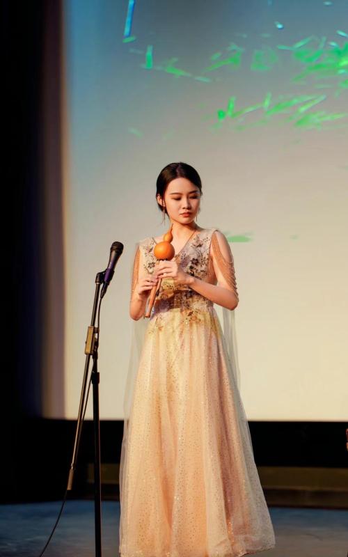 Ziyue Tan Woman in long dress standing by mirophone
