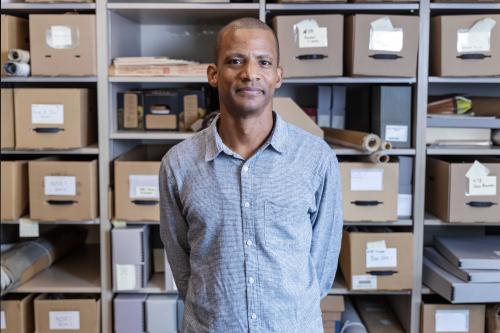 smiling young man standing in front of shelves of labeled boxes