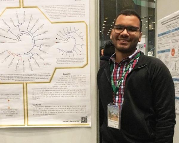 Andre Ordonez Casadiego stands next to a poster board of his work. 