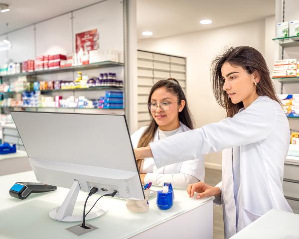 Two pharmacy technicians view a computer screen together. 