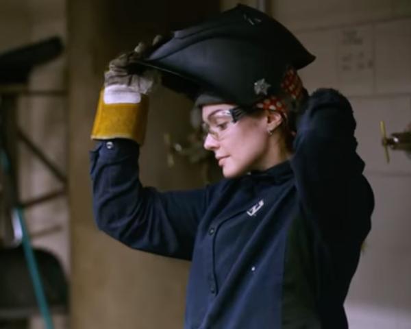 Rose Bleu, wearing protective gear, puts on a welding helmet.