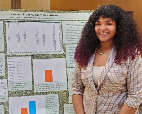 Student presents research at Minnesota State Capitol and stands in front of their presentation poster board