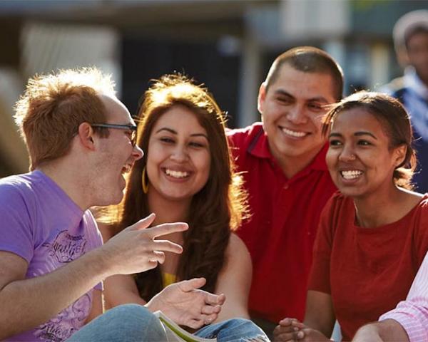 School of Liberal Arts and Cultures group of students socializing outdoors on a sunny day at Minneapolis College campus.