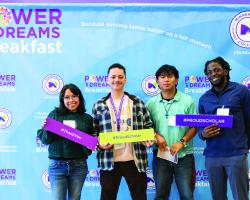Four students standing in front of a step-and-repeat that says Power of Dreams