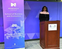 Student at podium with sign to her left that says School of Business and Economics 