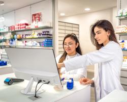 Two pharmacy technicians view a computer screen together. 