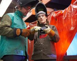 Welding Program at Minneapolis College instructor showing student welding solution with student working in the background