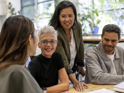 Four people in a workplace setting around a table talking