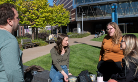 Four students outside in the courtyard talking