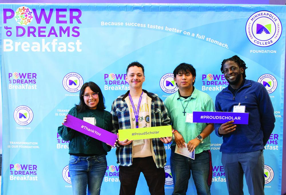 Four students standing in front of a step-and-repeat that says Power of Dreams