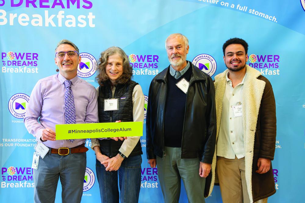 Four people stand together and smile for the camera in front of a step-and-repeat that says Power of Dreams